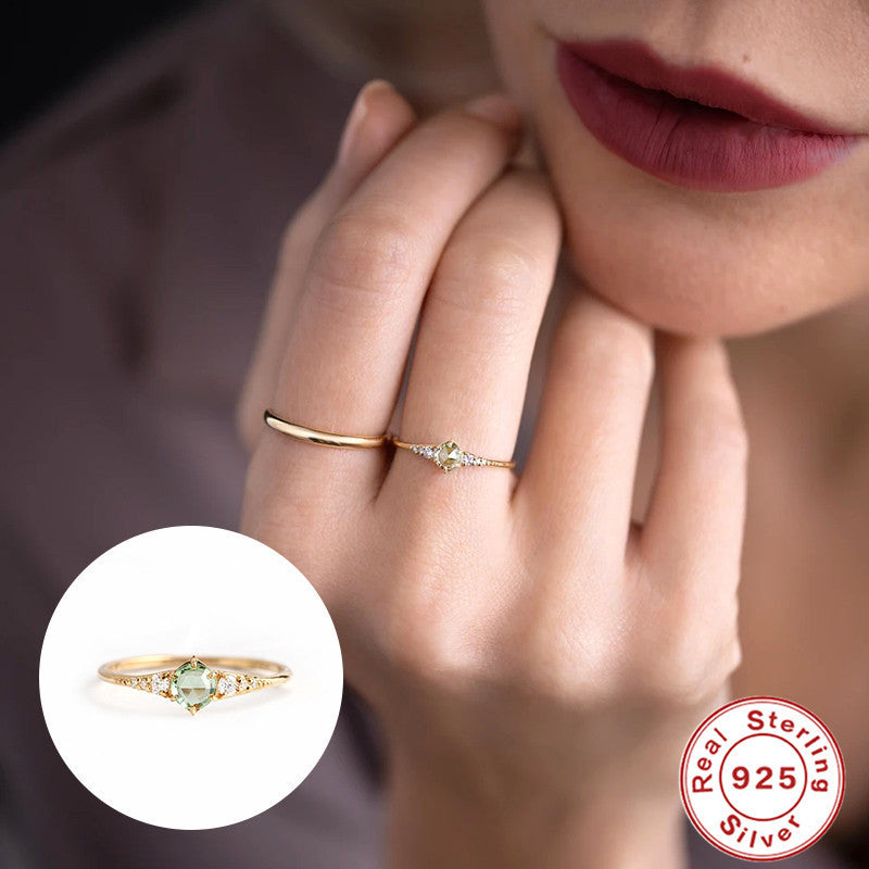 Women's rings are fashionable and luxurious accessories, modeled on hand with a close-up of the green gemstone and gold band design.