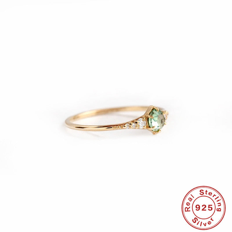 Women's rings are fashionable and luxurious accessories, highlighting a green gemstone set in a slim gold band with sterling silver base.
