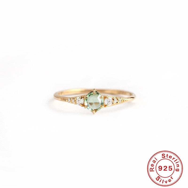 Women's rings are fashionable and luxurious accessories, featuring a centered green gemstone and diamond accents on a gold-plated silver band.